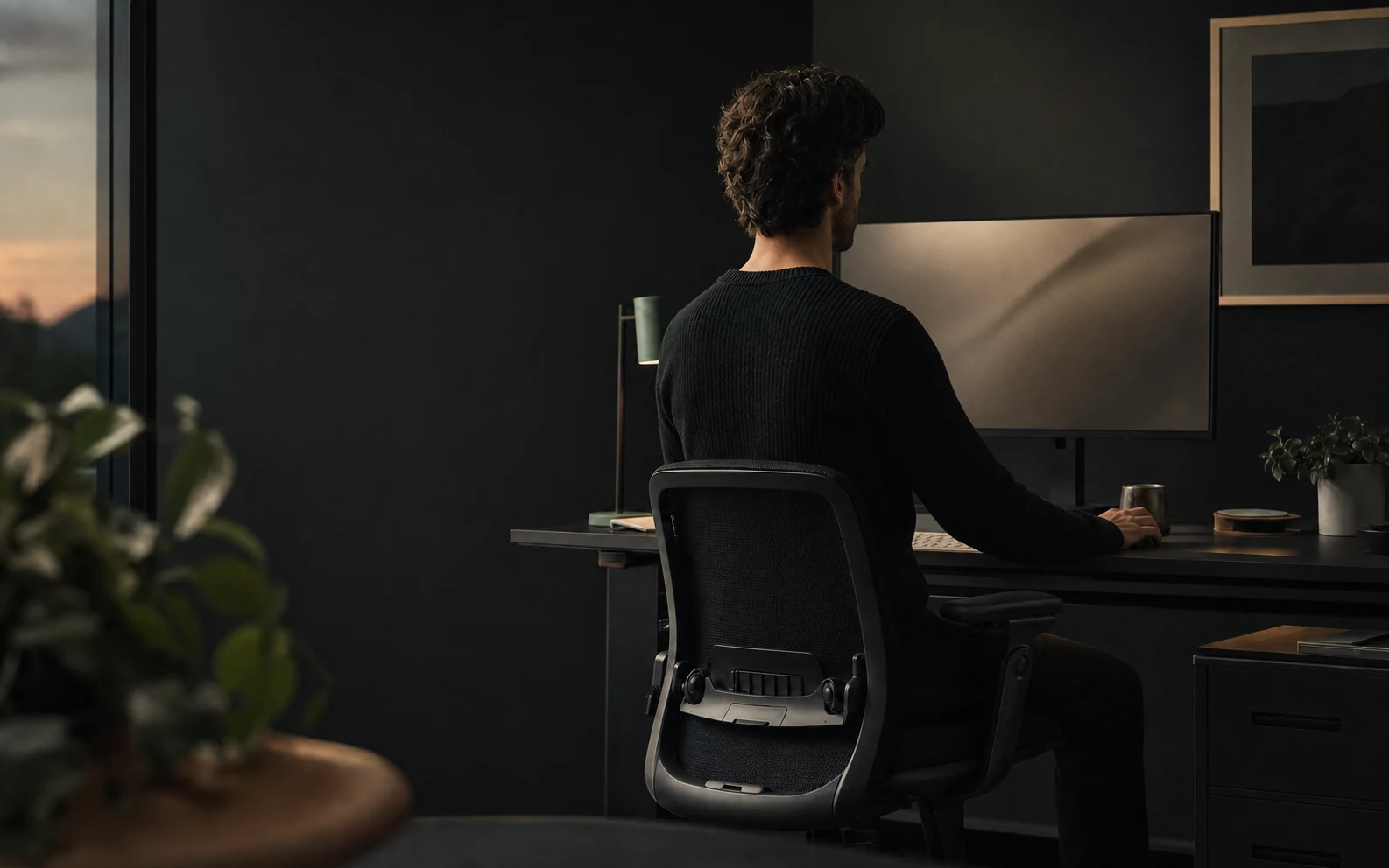 A person sitting upright at a desktop computer in a calm home office